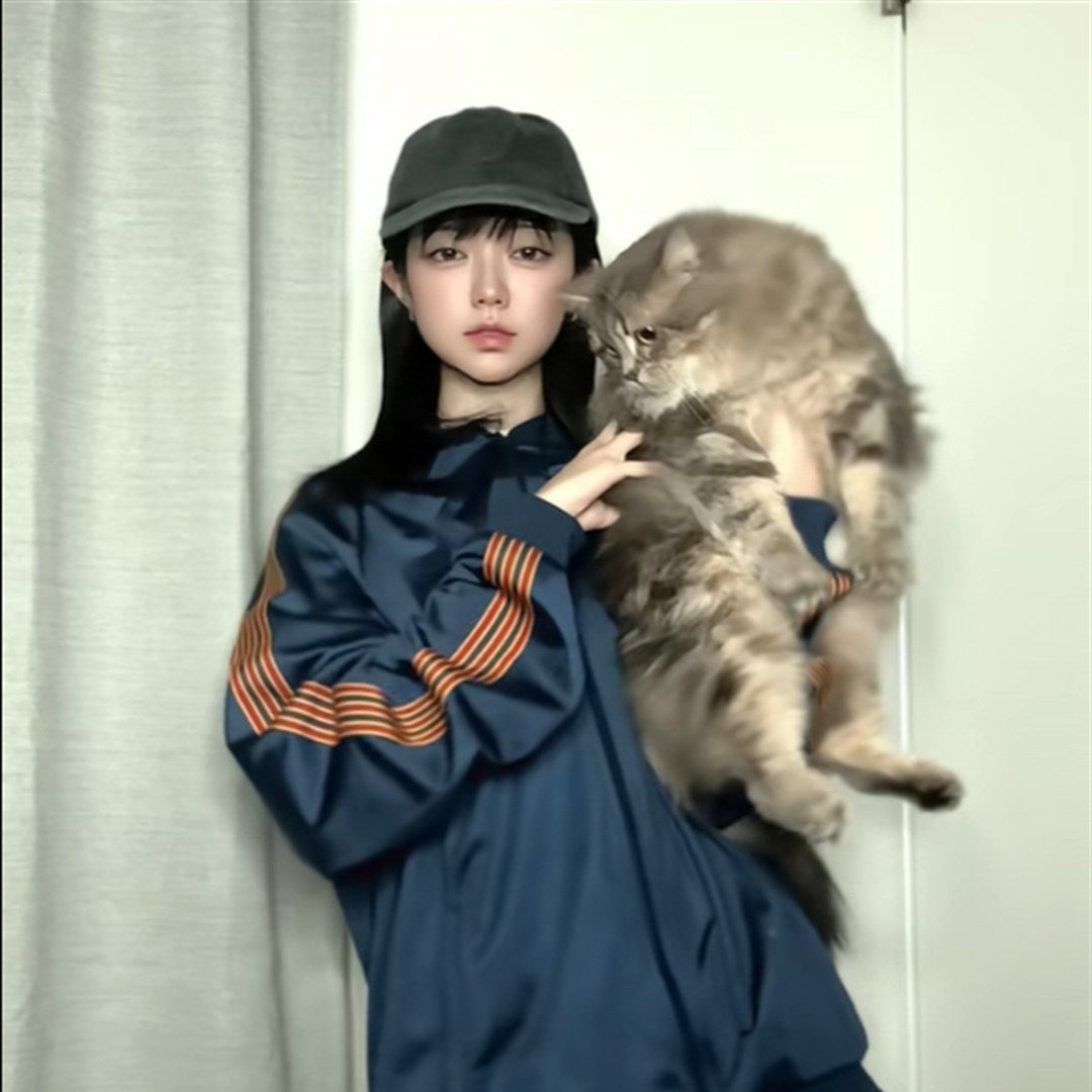 愛猫のぺちを抱きかかえるマリナ。ぺちは長毛の大きなキジトラ猫